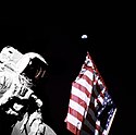 Astronaut NASA desfășurând steagul american în timpul unei faze de jumătate de fază a Pământului.  
