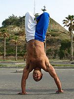 Een capoeirista voert een handstand uit met gebogen benen.