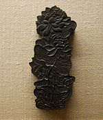 Una antigua barra de tinta china hecha en forma de hojas y flores de loto.  