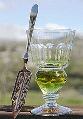 Reservoir glass with naturally coloured absinthe and absinthe spoon