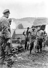Os soldados americanos do 3º Batalhão de Infantaria do 119º Batalhão dos EUA são feitos prisioneiros por membros do Kampfgruppe Peiper em Stoumont, Bélgica, em 19 de dezembro de 1944.