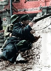 Vojak bataljona Kiliński meri s puško na stavbo PAST, ki so jo zasedli Nemci, 20. avgust 1944