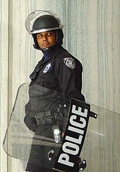Een Amerikaanse politieagent draagt een helm en draagt een oproerschild. Oktober 2002