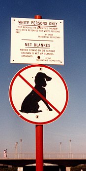 Bordje bij een strand met de tekst 'zwarten en honden zijn niet toegestaan'.
