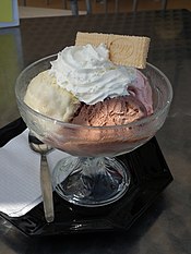 Înghețată de vanilie, ciocolată și căpșuni cu frișcă într-un bol  