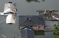 Mensen op de daken van hun huizen, om het overstromingswater te ontwijken