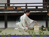 Een vrouw in kimono voert een theeceremonie uit.  