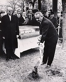 Roger L. Stevens (links) kijkt toe terwijl President Johnson op 2 december 1964 aan de slag gaat. Deze foto is gesigneerd door Johnson aan Stevens.