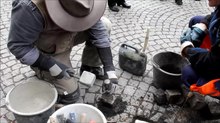 Play media file Video: Gunter Demnig divides a paving stone with a chisel and a hammer while laying a Stolperstein in Cologne.