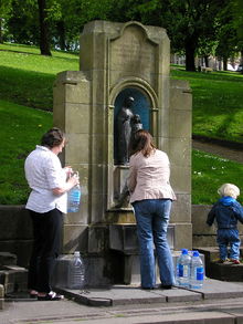 Menschen füllen am St. Ann-Brunnen Flaschen mit Wasser auf
