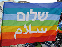 Rainbow flag at an Easter march with the Hebrew spelling for shalom and the Arabic for Salām