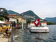 The city centre lies on the shores of Lake Lugano, with Monte Brè in the background.