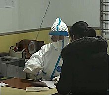 Doctor in protective suit interviewing patients at Wuhan hospital in January 2020