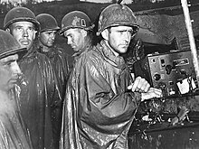 1945 m. gegužės 8 d. 77-osios divizijos amerikiečių kariai ramiai klausosi radijo pranešimų apie Pergalės Europoje dieną.