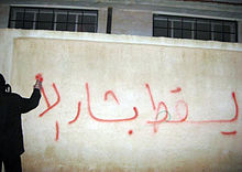 Een Syrische demonstrant spuit anti-Bashar al-Assad graffiti tijdens de Arabische Lente in Syrië