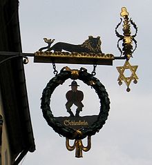 Znak nad vhodom, ki prikazuje moškega z visečimi rokami