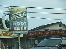 Root beer-skylt som visar den typiska muggen och den skummande toppen.  