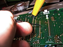 Measurement on a circuit board with a multimeter or oscilloscope, typical activity in hardware hacking.