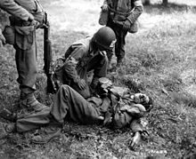 A U.S. Army medic kneels next to a wounded German soldier during the invasion of Normandy, 1944.