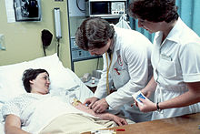 El médico, con una enfermera a su lado, está realizando un análisis de sangre en un hospital en 1980