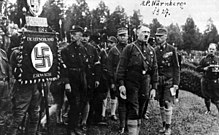Adolf Hitler in 1927 as a speaker at the third Reich Party Congress of the NSDAP (the first in Nuremberg). Heinrich Himmler, Rudolf Heß, Franz Pfeffer von Salomon and Gregor Strasser can be seen in the background.