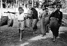 Drie vrouwen en twee jongens uit West-Sulawesi verkopen houtskool. Koloniale periode, 1937.  