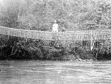 Een Europeaan staat op een rotan brug in Mamasa, Toradja Land, Celebes  