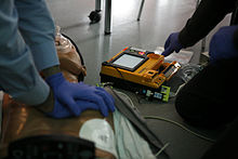 Carrying out basic measures on a model, with a defibrillator in the background
