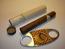 Eine Zigarre mit Vorratsröhrchen und Zigarrenschneider.