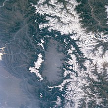The Kashmir Valley (centre) in a satellite photo. The snow-covered mountains separate it from the plains.