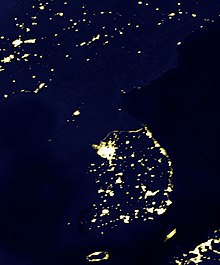 Het Koreaanse schiereiland bij nacht, met een contrast tussen het helder verlichte Zuid-Korea en het overwegend donkere Noord-Korea.  