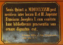 O latim nesta placa está escrito: "No ano de 1883, após o meio-dia da segunda e terceira horas, o Imperador Francisco José, com uma companhia de pessoas, dignou-se a honrar esta biblioteca com sua presença".