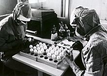 Dois trabalhadores fazem aberturas em ovos de galinha enquanto se preparam para fazer vacinas contra o sarampo