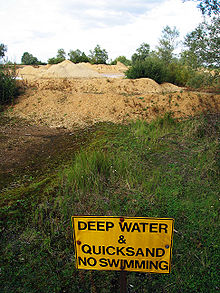 Kruusakarjääri kaevandamiskohas asuv jooksev liiv ja hoiatusmärk.