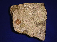 Minério de terra rara, mostrado com um centavo dos Estados Unidos para comparação de tamanho