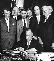 Franklin D. Roosevelt (seated) and George W. Norris (front right) at the founding of the Tennessee Valley Authority (1933)