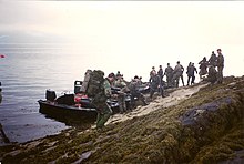 Brittiska Royal Marines går i land från sin Rigid Raider-landningsbåt på en strand under en övning.  