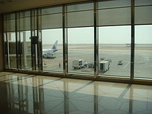 Een B737 van Sama Airlines geparkeerd op de luchthaven, op weg naar Medina. Zicht vanuit de vertrekhal van de terminal.  
