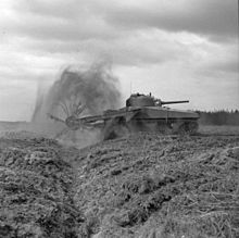 M4 Sherman mine sweeping tank with rear-facing gun turret in action. The front-mounted threshing device detonates mines.