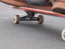 Partea inferioară a unei plăci de skateboard. În această fotografie pot fi văzute puntea, roțile și roțile.  