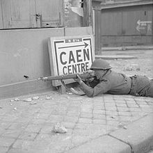 A British soldier keeps a lookout for German snipers in fiercely contested Caen, 9 July 1944.