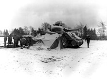 First U.S. Army tank soldiers gather around a fire on snow-covered ground near Eupen, Belgium, and open their Christmas packages (Dec. 30, 1944)