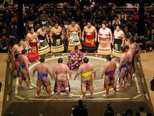 Bojovníci sumo při zahajovacím ceremoniálu obíhají rozhodčího.