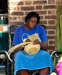 一位古拉妇女在查尔斯顿的城市市场制作甜草篮子
