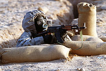 Un soldato in Siria, con un fucile AK-47 e una maschera antigas