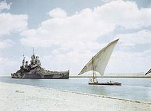 The British battleship HMS Howe (32) with a felucca in the Suez Canal, 14 July 1944.