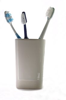 Drie plastic tandenborstels in een beker  