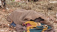 Burundi põllumees magab teki all.