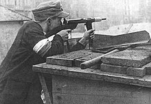 Yksi Armia Krajowan sotilaista puolustamassa barrikadia Powiślen alueella Varsovan kansannousun aikana. Mies on aseistettu Błyskawica-konepistoolilla.