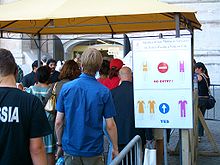 Ein Schild informiert Touristen über die Mindestkleidungsstandards, die zum Betreten des Petersdoms im Vatikan erforderlich sind